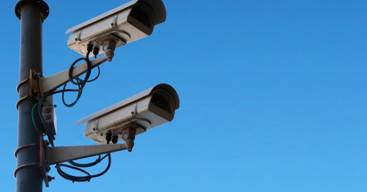 Two weatherproof CCTV cameras mounted on a steel pole against a clear UAE sky